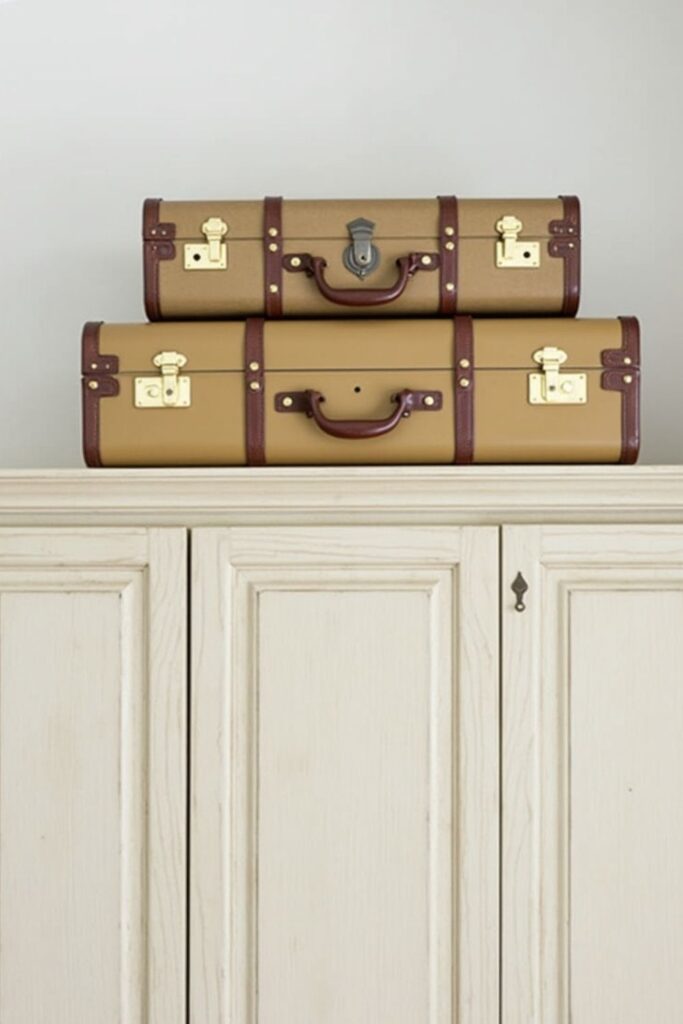 stacked vintage suitcases above kitchen cabinets used as enclosed dust free storage decor